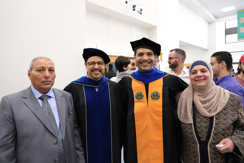 Mohammad, in regalia, with three others at doctoral hooding ceremony.